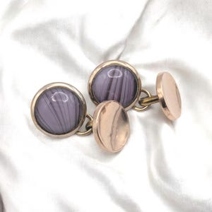 Puede incluir: Un par de gemelos de oro con un diseño de piedra de ágata rayada en morado y blanco.