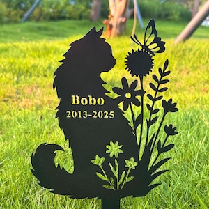 Op de afbeelding: Zwarte metalen tuinpaal met een katten silhouet, bloemen en een vlinder. De tekst "Bobo 2013-2025" is goudkleurig. Ontworpen om in een tuin of gazon te plaatsen.