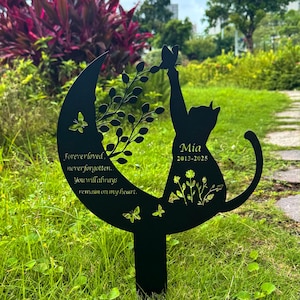 May include: Black metal garden stake with a cat silhouette reaching for a butterfly. The stake includes the name "Mia" and dates 2013-2025, along with the text "Forever loved, never forgotten. You will always remain on my heart."