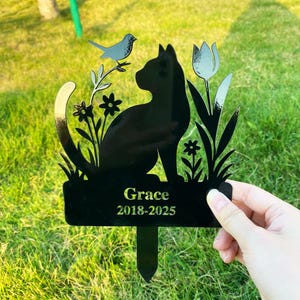 Puede incluir: Estaca de jardín conmemorativa para gatos de metal negro con un gato, un pájaro, flores y un diseño de tulipán. La estaca dice "Grace 2018-2025". El gato está sentado y el pájaro está posado en una rama.