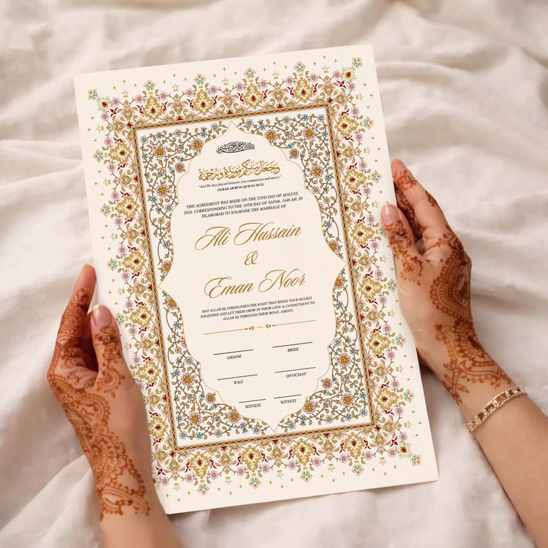 Puede incluir: Un certificado de matrimonio color crema con un borde floral dorado, rojo y verde adornado. El documento presenta los nombres "Ali Hussain & Eman Noor" en una escritura elegante. Las manos que sostienen el certificado est&aacute;n decoradas con henna.