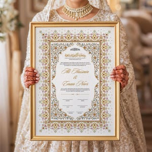 Puede incluir: Un certificado de boda enmarcado con borde dorado, sostenido por una persona. El certificado presenta dise&ntilde;os florales ornamentados en oro, rojo y verde, con escritura &aacute;rabe y los nombres "Ali Hussain & Eman Noor".
