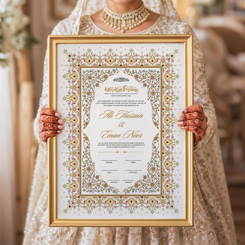 Puede incluir: Un certificado de boda enmarcado con borde dorado, sostenido por una persona. El certificado presenta dise&ntilde;os florales ornamentados en oro, rojo y verde, con escritura &aacute;rabe y los nombres "Ali Hussain & Eman Noor".