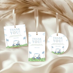 Puede incluir: Tres etiquetas de agradecimiento con temática de golf con cintas blancas. Cada etiqueta presenta un carrito de golf, banderas y el texto "THANK YOU!" en azul. Las etiquetas son cuadradas, rectangulares y circulares.