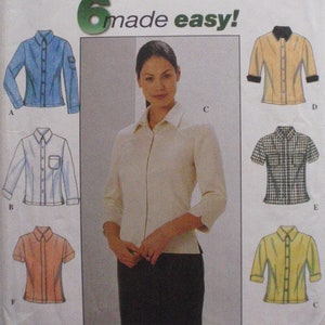May include: A Simplicity sewing pattern envelope 8872 for shirts in sizes 14, 16, 18, and 20. The package features illustrations of six different shirt styles with varying sleeve lengths, collar designs, and patterns, including solid blue, white, peach, yellow, and a black and white check.