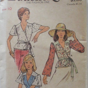 Op de afbeelding: Vintage Butterick naaipatroon 3554, met illustraties van wikkel tops met verschillende mouwstijlen en striksluitingen. Het patroon bevat maten 8-16 en de prijs is $1.00. De tekst "THE FASHION ONE" is ook zichtbaar.