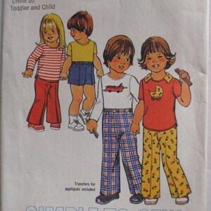 Puede incluir: Patrón de costura Simplicity número 7061 para ropa de niños pequeños y niños. El patrón incluye cuatro diseños: una camisa de manga larga a rayas rojas y blancas con pantalones rojos, una camisa de manga corta amarilla con pantalones cortos azules, una camisa de manga corta blanca con un camión rojo y pantalones a cuadros, y una camisa de manga corta roja con un gráfico de cochecito de bebé y pantalones florales. El patrón es solo para tejidos de punto elásticos.