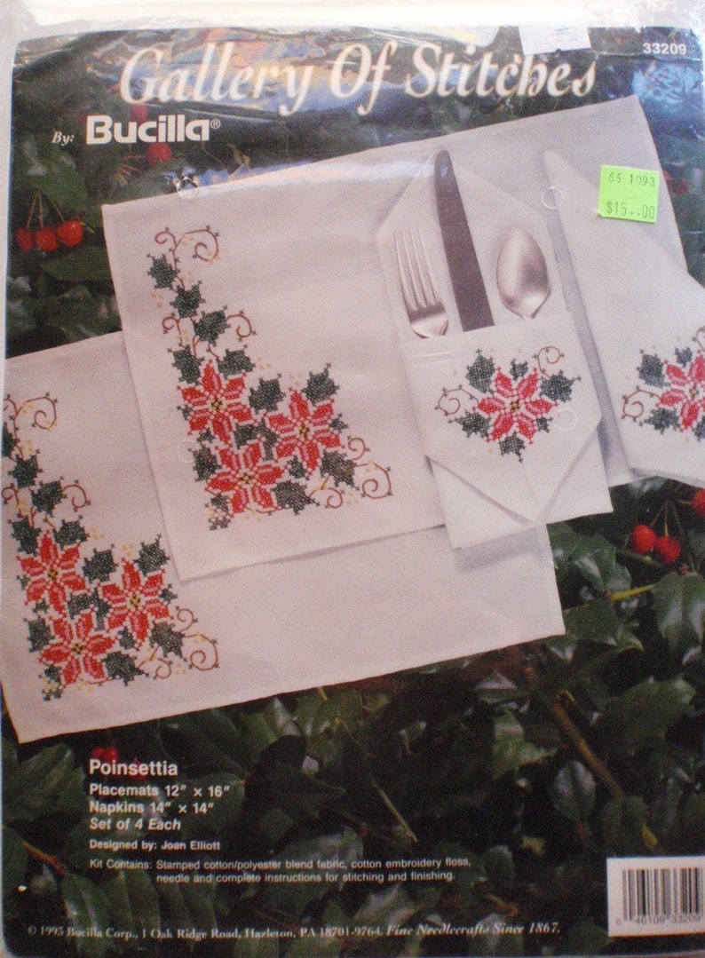 May include: A Bucilla Gallery of Stitches kit featuring a poinsettia design. The kit includes four pieces: two 12" x 16" placemats and two 14" x 14" napkins. The white fabric is adorned with red and green cross-stitch poinsettias.