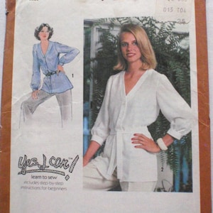 May include: Simplicity sewing pattern 9265, size 18 Misses. The pattern features a woman wearing a white button-down top with a belt and pants. The pattern includes step-by-step instructions for beginners. The pattern's cover is tan and white.