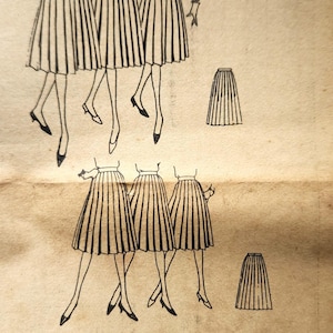 May include: A vintage Simplicity primer sewing pattern 3561 for a pleated skirt. The paper envelope features black line illustrations of skirts on figures, text including Simplicity primer 3561, and instructions for tall, medium, and short heights.