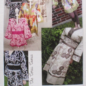May include: A sewing pattern for The Torii Tunic, featuring multiple tunic designs with various patterns and colors. The image showcases several finished tunics, including floral and abstract prints, with details like belts and sleeve variations. The pattern includes instructions for sizes XXS-XXL.