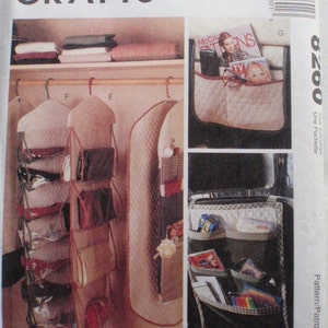 Puede incluir: Patrón de McCall's Crafts para organizadores de almacenamiento. La imagen muestra ejemplos de organizadores terminados, incluido un organizador colgante de bolsos y un organizador de asiento de automóvil. El patrón incluye instrucciones para organizadores con múltiples bolsillos.