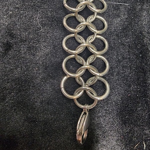 May include: A silver chainmail bracelet with a lobster clasp closure.