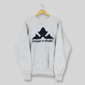 May include: A heather gray sweatshirt with a black graphic of three stylized shapes and the text "KAHULA O HAWAII" in a handwritten font. The sweatshirt is hanging on a wooden hanger against a light gray background.