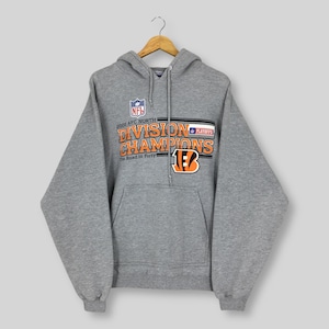 May include: A heather gray hooded sweatshirt featuring a graphic print that reads 2005 AFC NORTH DIVISION CHAMPIONS The Road to Forty with an NFL logo, a Playoffs patch, and a Cincinnati Bengals tiger stripe B logo in orange, black, and white.