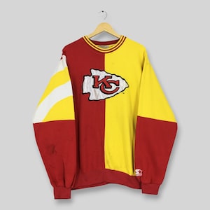 May include: A vintage Kansas City Chiefs sweatshirt in red and yellow. The sweatshirt features the Chiefs logo on the front and a Starter logo on the sleeve. The design is split vertically, with red on the left and yellow on the right.