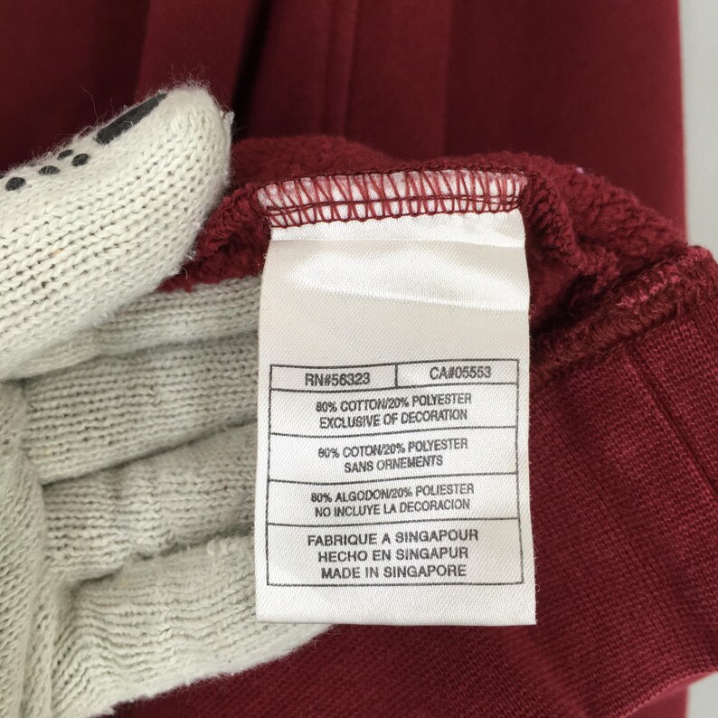 Może przedstawiać: Biały ceramiczny kubek z kolorowym kwiatowym wzorem. Kubek posiada uchwyt i błyszczące wykończenie. Kwiaty są w odcieniach r&oacute;żu, fioletu i ż&oacute;łci. Kubek jest prawdopodobnie przeznaczony do gorących napoj&oacute;w.