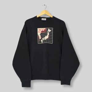 May include: Black Champion sweatshirt with a graphic featuring a map of Japan and the text "2002 FIFA World Cup". The graphic is in red and white, set against a white grid. The sweatshirt has a crew neck and long sleeves.