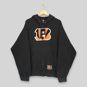 May include: Black zip-up hoodie with a large orange and white "B" logo on the front. The hoodie has a hood, a front pocket, and a small patch near the bottom. The hoodie is hanging on a wooden hanger.