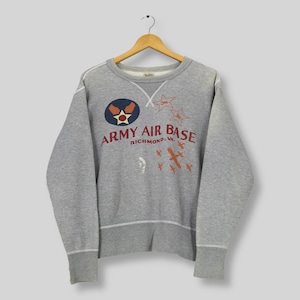 May include: A gray sweatshirt with the text "Army Air Base Richmond, VA" in red and a circular emblem. The emblem features a star and wings. The design includes orange stars and airplanes. The sweatshirt has white trim.