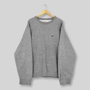 May include: A set of three ceramic mugs with a speckled, matte finish. The mugs are in shades of cream, light gray, and dark gray. Each mug has a simple, minimalist design, perfect for coffee or tea.