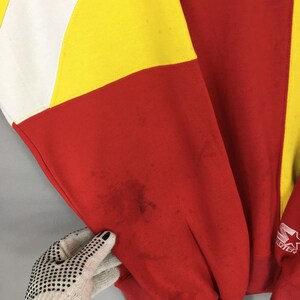 May include: A vintage red, yellow, and white color-block sweatshirt. The sleeve is red with a yellow and white section. The Starter logo is visible on the sleeve. The sweatshirt shows signs of wear with some stains.