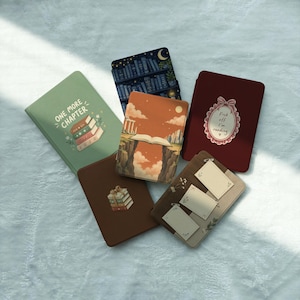 May include: Five e-reader cases featuring various designs: a sage green case with a stack of books and text reading ONE MORE CHAPTER, a dark blue bookshelf print, an orange landscape with an open book, a dark red case with a pink oval frame and text reading F*ck off I'm reading, and a brown case with three blank labels.