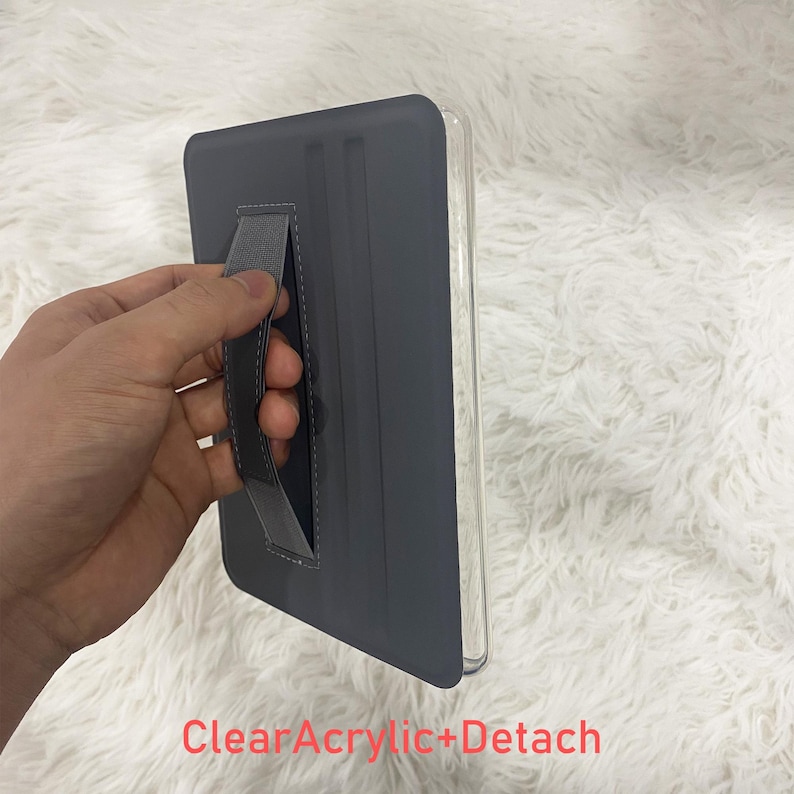 May include: A grey tablet case featuring a clear acrylic back and a detachable hand strap. The case has a smooth, matte finish on the front cover and includes the text ClearAcrylic+Detach printed in red at the bottom of the image.