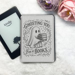 May include: A light gray Kindle cover with a ghost illustration holding books, surrounded by the text "Ghosting You For My Books." A Kindle e-reader is visible to the left. The cover is a book accessory.
