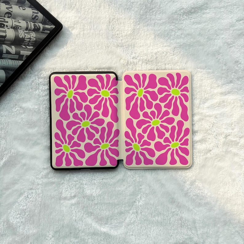 May include: A rectangular e-reader case featuring a cream-coloured background with a repeating pattern of vibrant magenta flowers with bright lime green centres. The case is shown in an open position, displaying the interior and exterior panels.
