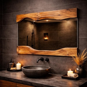 May include: A rectangular mirror with a live edge wooden frame. The frame is a light brown colour with a natural, wavy edge. The mirror is mounted above a dark grey countertop with a black tap and a dark grey stone sink. Candles and decorative items are on the countertop.