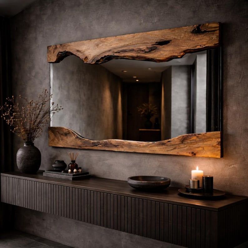 May include: A large rectangular mirror with a natural wood frame. The frame has a live edge design, showcasing the wood's unique shape and texture. The mirror is mounted on a dark gray wall above a dark wood console table.