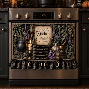 May include: A black oven towel featuring the text Olivia's Kitchen Seasoned with Intention, surrounded by illustrations of a cauldron, candle, garlic, mortar and pestle, crystals, and books labeled Tea Leaves, Crystals, Tarot, Divination, and Manifestation.