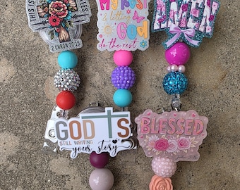 May include: A collection of five badge reels with inspirational quotes. Each reel features a unique design with colorful beads and a retractable cord. The quotes include "This is how I fight my battles," "Doing my best & letting God do the rest," and "Blessed."