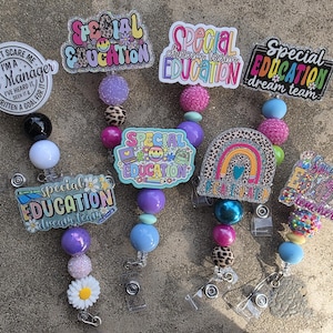 Puede incluir: Una colección de coloridos portatarjetas con varios diseños y textos, incluyendo "Special Education Dream Team" y "Case Manager". Los portatarjetas presentan cuentas de varios colores y patrones, con una margarita y un arcoíris.