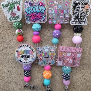 May include: Seven badge reels featuring radiology-themed designs with colorful beads. The designs include text like Radiology Crew, Radiology Tech, and You Pose We Expose, alongside medical icons, skeletons, and cartoon characters on acrylic toppers.