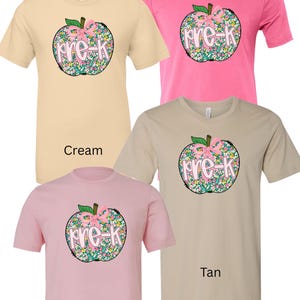 May include: Four short-sleeved t-shirts in cream, charity pink, pink, and tan. Each shirt features a floral apple design with the text "pre-k" in pink. The shirts are suitable for preschool.