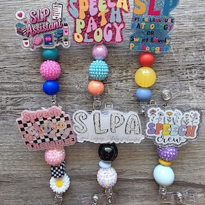 May include: Six badge reels featuring acrylic toppers with text including SLP Assistant, Speech Pathology, SLP Sweet Lovely Pathologist, Speech Therapist, SLPA, and Speech Crew. Each reel has a strand of colourful, textured, and patterned beads.