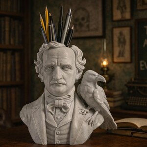 May include: A white bust of a man with a raven on his shoulder, holding pens and pencils. The bust is on a wooden desk with books and a chalkboard that reads "THE ANSWER TO EVERYTHING".