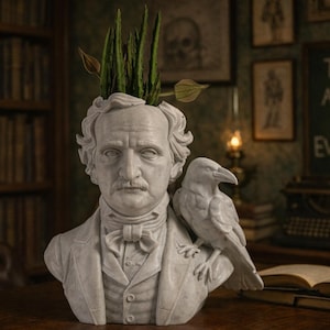 May include: A white bust of Edgar Allan Poe with a raven perched on his shoulder, used as a planter for green plants. The bust is on a wooden table, with a chalkboard that says "THE ANSWER TO EVERYTHING" in the background.