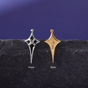 May include: A four-pointed star-shaped earring shown from two angles. The front view is silver-toned with black enamel detailing. The back view is gold-toned with a post and the text 925 stamped on the surface. The word Front is below the silver earring and the word Back is below the gold earring.