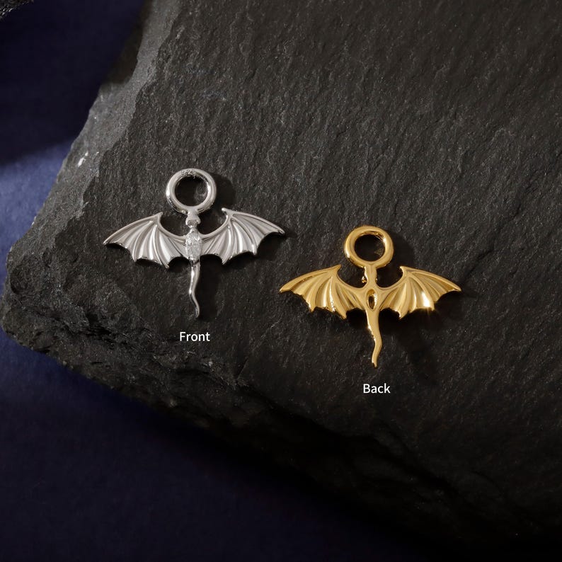 May include: Two dragon-shaped pendants, one silver and one gold, are shown against a dark background. The silver pendant is labelled "Front," and the gold pendant is labelled "Back." Each pendant features a dragon with outstretched wings and a curled tail.