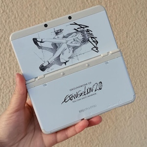 May include: A white handheld gaming console featuring a black and white illustration of a character on the top screen area and the text Groundwork of Evangelion: 2.0 You Can (Not) Advance and Japanese characters on the bottom section.