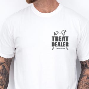 K&ouml;nnte beinhalten: Wei&szlig;es T-Shirt mit schwarzem Aufdruck. Der Aufdruck zeigt den Text "TREAT DEALER", eine Hunde-Silhouette und die Namen "ZAHRA &bull; RUBY". Das T-Shirt hat einen Rundhalsausschnitt.