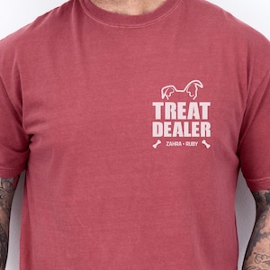 K&ouml;nnte beinhalten: Karmesinrotes T-Shirt mit dem wei&szlig;en Text "TREAT DEALER", einer Hunde-Silhouette und den Namen "ZAHRA &bull; RUBY". Das Shirt ist einfarbig und hat einen Rundhalsausschnitt.