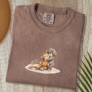 Monkey Punch Comfort Colors T-shirt, T-shirt met babyaapje dat een knuffel vasthoudt, cadeau voor dierenliefhebbers, virale meme van een verdrietig aapje, grafisch T-shirt voor mama en kind. Espresso