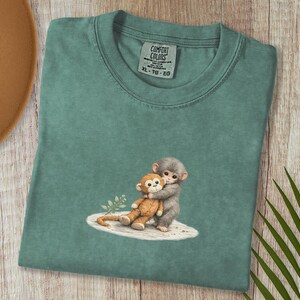 Monkey Punch Comfort Colors T-shirt, T-shirt met babyaapje dat een knuffel vasthoudt, cadeau voor dierenliefhebbers, virale meme van een verdrietig aapje, grafisch T-shirt voor mama en kind. Light Green