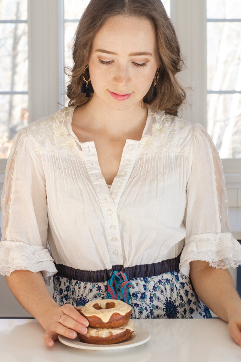 A woman putting sourdough donuts on a plate.