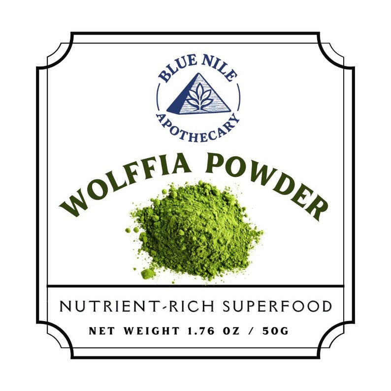 May include: A white label with a black border features the text "BLUE NILE APOTHECARY" and "WOLFFIA POWDER". A pile of green powder is in the center. The text "NUTRIENT-RICH SUPERFOOD" and "NET WEIGHT 1.76 OZ / 50G" are also present.