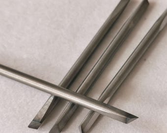Könnte beinhalten: Vier silberne Metallmeißel mit abgeschrägten Kanten.